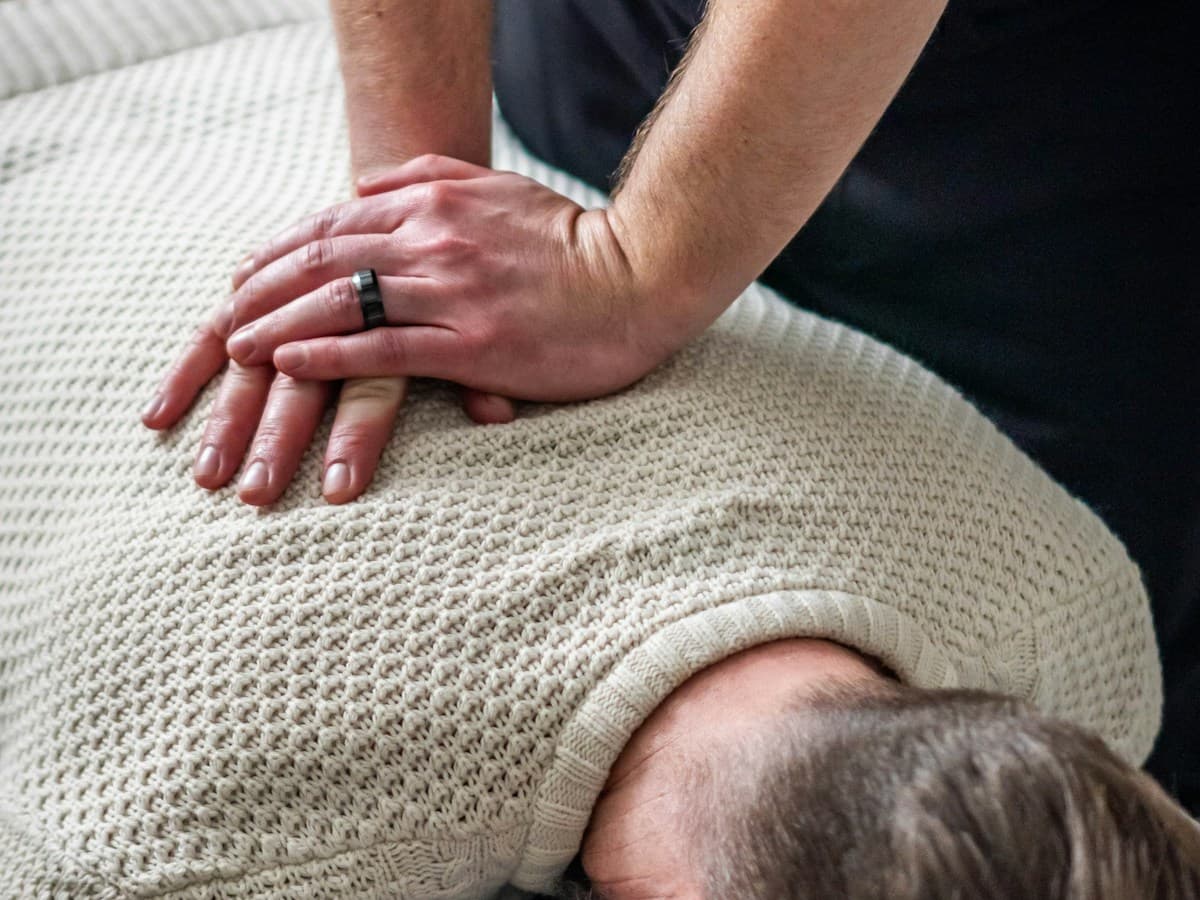 Clinician performing a careful upper back and neck adjustment in a treatment room
